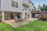 Exterior elevation featuring a multi-level layout with siding, a ground-level patterned paver patio, an elevated deck with railings, and sliding glass