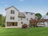 Exterior featuring multi-level siding, elevated deck with stairs, stone-paver patio, and integrated covered area