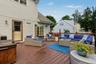 Expansive rear deck with integrated hot tub, and wood-toned railing featuring overhead string lighting