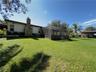 Expansive backyard featuring a large grass lawn, stone-faced exterior chimney, and a screened-in rear enclosure