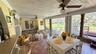 Enclosed sunroom featuring tile flooring, beadboard wood-paneled ceiling, ceiling-mounted fans, wall-mounted light fixtures, and a metal railing parti