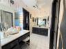 Double vanity with dark cabinetry, white countertops, ceramic tile flooring, built-in vanity station, and ceiling-mounted lighting