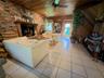 Exposed brick fireplace with a wood mantel, wood-paneled ceiling, diagonal wood wall paneling, and tile flooring