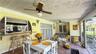 Covered patio featuring ceramic tile flooring, beadboard ceiling, built-in exterior bar counter, dual ceiling fans, and wrought iron railings