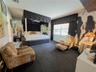 Spacious room featuring floor-to-ceiling mirrored walls, a custom built-in elevated platform, and a large multi-pane window with custom valance