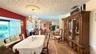 Dining area featuring an ornate crystal chandelier with ceiling medallion, built-in window seating, decorative textured ceiling, and stone flooring