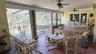 Covered patio featuring ceramic tile flooring, stone-veneer retaining wall, white metal railing, and dual ceiling fans