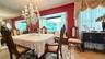 Formal dining area featuring a crystal chandelier, built-in window seating, wall-to-wall mirror paneling, and natural stone flooring