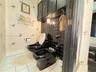 Black toilet and bidet fixture set, wall-mounted black cabinetry, black grid-pattern tile backsplash, and wall-mounted light fixture