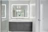 Floating vanity with dark wood-finish cabinetry, white countertop, integrated rectangular sink, wall-mounted faucet, and rectangular LED-backlit mirro