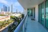 Covered balcony featuring large-format stone-finish flooring, glass panel railings, and floor-to-ceiling glass sliding doors