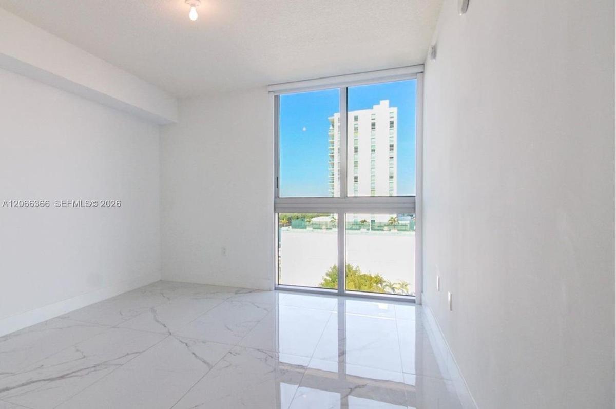 Large-format light-toned tile flooring with grey veining, floor-to-ceiling windows, and recessed ceiling lighting