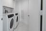 Laundry room featuring white stone-finish tile flooring, built-in upper cabinetry, and a flush-mount utility access panel