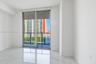 Large-format white tile flooring, floor-to-ceiling glass sliding doors, and a metal-railed exterior balcony