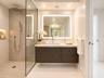 Floating vanity with a stone countertop, rectangular vessel sink, frameless glass shower enclosure, integrated shower wall niche, and rectangular LED-