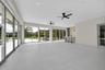 Large-format porcelain tile flooring, expansive floor-to-ceiling sliding glass doors, built-in wet bar with wood-panel detailing, recessed lighting, a