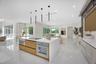 Modern kitchen featuring a central island with integrated cooktop and oven, sleek flat-panel cabinetry, light-toned stone-surface countertops, recesse