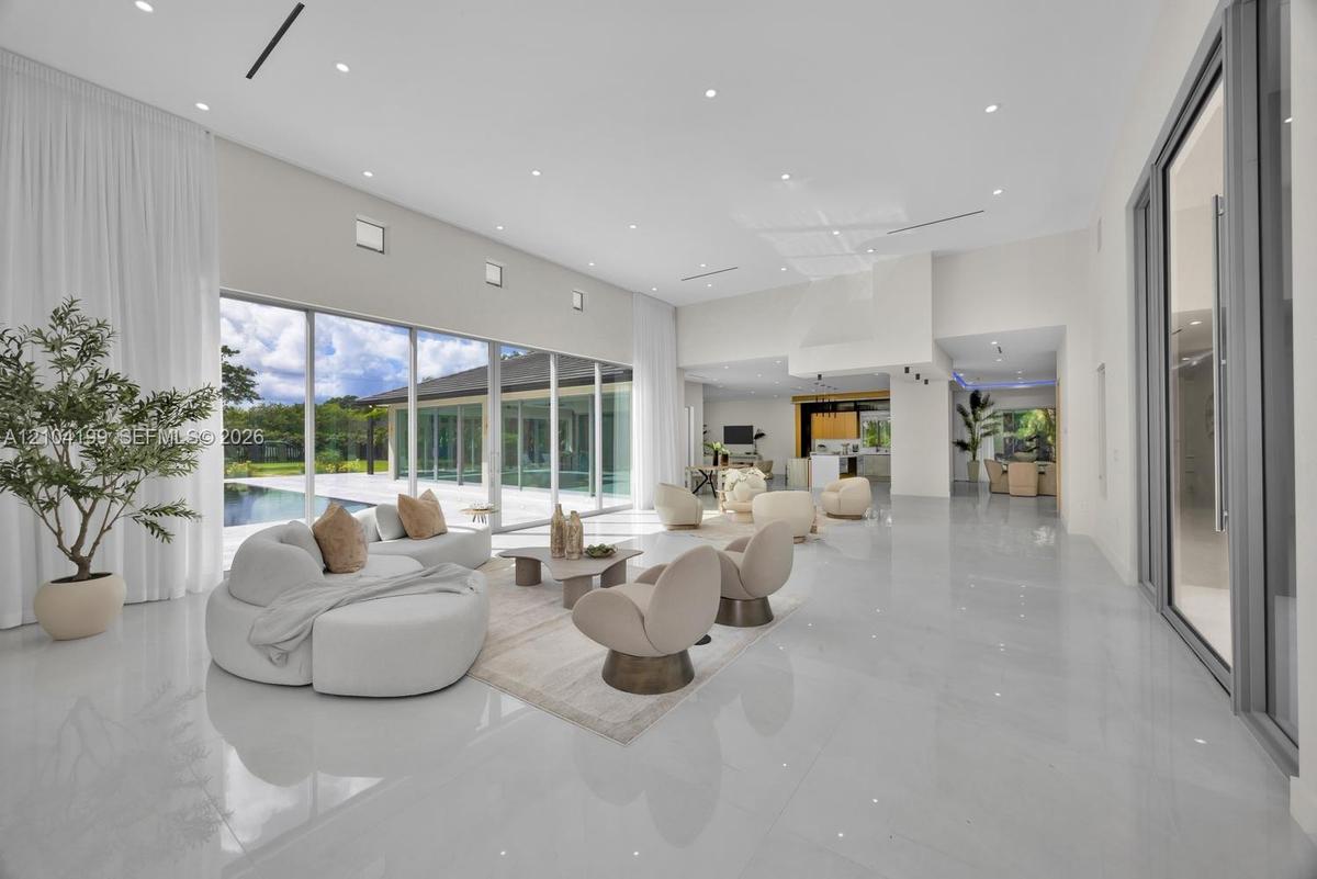 Expansive open-concept room featuring high ceilings with recessed lighting, large-format polished tile flooring, and floor-to-ceiling glass sliding do
