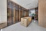 Custom storage system featuring floor-to-ceiling cabinetry with glass-panel doors, integrated LED lighting, central built-in island with storage drawe
