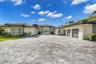 Single-story estate featuring a multi-car garage, a paver driveway, light-toned exterior finish, and a covered entryway