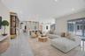 Open-concept interior featuring large-format tile flooring, recessed ceiling lighting, a waterfall-edge kitchen island, metallic accent detailing, and