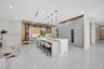 Custom kitchen featuring a stone-topped waterfall island, full-height cabinetry with integrated refrigeration, metallic-tone upper accent cabinets, an