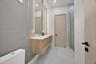 Floating wood-finish double vanity with integrated sinks, dual backlit mirrors, matte black hardware, and a walk-in shower with large-format tile surr