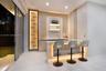 Built-in bar featuring wood-finish cabinetry, stone-surfaced countertop, vertical accent paneling, integrated recessed shelving, and under-counter lig
