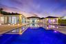 Contemporary residence featuring an infinity-edge pool, stone-paved patio, recessed exterior lighting, and floor-to-ceiling glass sliding doors