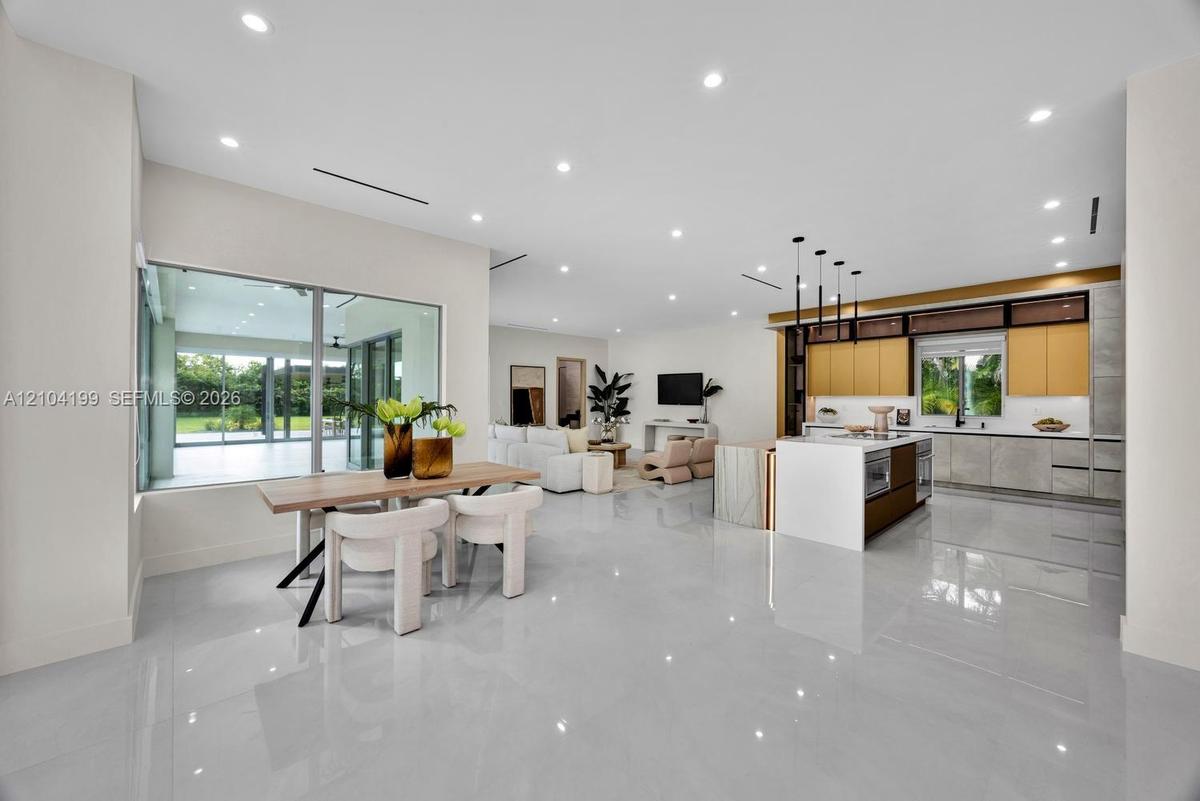 Open-concept interior featuring large-format tile flooring, recessed lighting, and a kitchen equipped with a central island and contemporary flat-pane