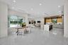 Open-concept interior featuring large-format tile flooring, recessed lighting, and a kitchen equipped with a central island and contemporary flat-pane