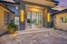 Modern exterior entrance featuring a glass-panel pivoting entry door, dual elevated concrete steps with integrated lighting, sleek vertical wall sconc