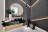 Floating vanity with stone countertop and matte black vessel sink, circular backlit mirror, vertical slat wood accent paneling, integrated recessed co