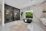 Bathroom featuring floor-to-ceiling stone wall cladding, a freestanding oval soaking tub, a smoked-glass enclosed shower, a floating vanity with stone
