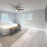Wood-finish flooring, multi-pane windows with integrated shutters, neutral wall paint, and a ceiling-mounted light fixture with a fan