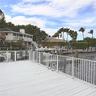 Waterfront wood-finish deck with whitenmetal safety railings and integrated dock ladder