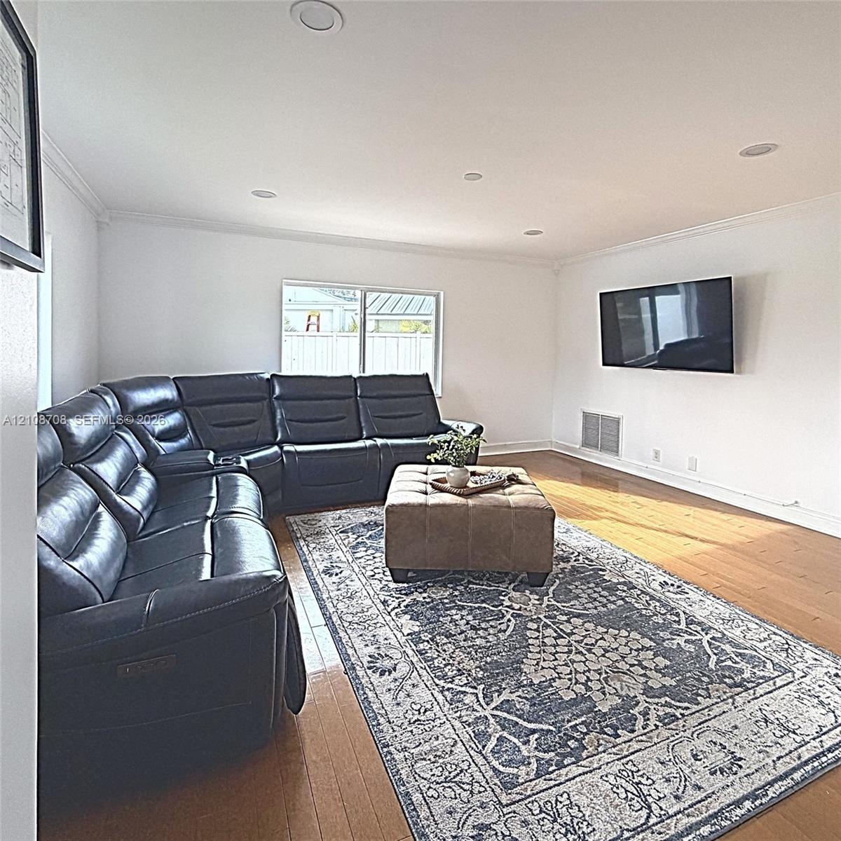 Living area featuring wood-finish flooring, recessed lighting, and crown molding