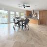 Large-format stone tile flooring, wooden cabinetry, stainless steel range hood, recessed lighting, and expansive glass paneled doors