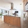 Kitchen island featuring stone countertops, integrated cooktop, stainless steel ceiling-mounted range hood, recessed lighting, and tile flooring