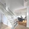 Foyer featuring a staircase with painted wood railings and balusters, stone-finish flooring, and crown molding