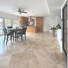 Open-concept kitchen featuring natural stone tile flooring, wood cabinetry, a stainless steel range hood, recessed lighting, and glass-paneled sliding