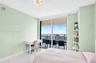 Room with large glass sliding doors, polished stone-finish flooring, and built-in white shelving, providing access to a private balcony