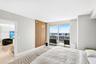 Room featuring floor-to-ceiling glass sliding doors, wood-slat accent wall, tile flooring, and integrated ceiling lighting