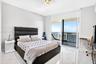 Floor-to-ceiling sliding glass doors, white large-format stone-finish flooring, and recessed ceiling lighting