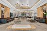 Expansive room featuring cylindrical wood-finished support columns, custom multi-cluster decorative chandeliers, recessed tray ceiling lighting, and a