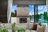 Stone-clad exterior fireplace, expansive sliding glass wall system, and glass panel balcony railing