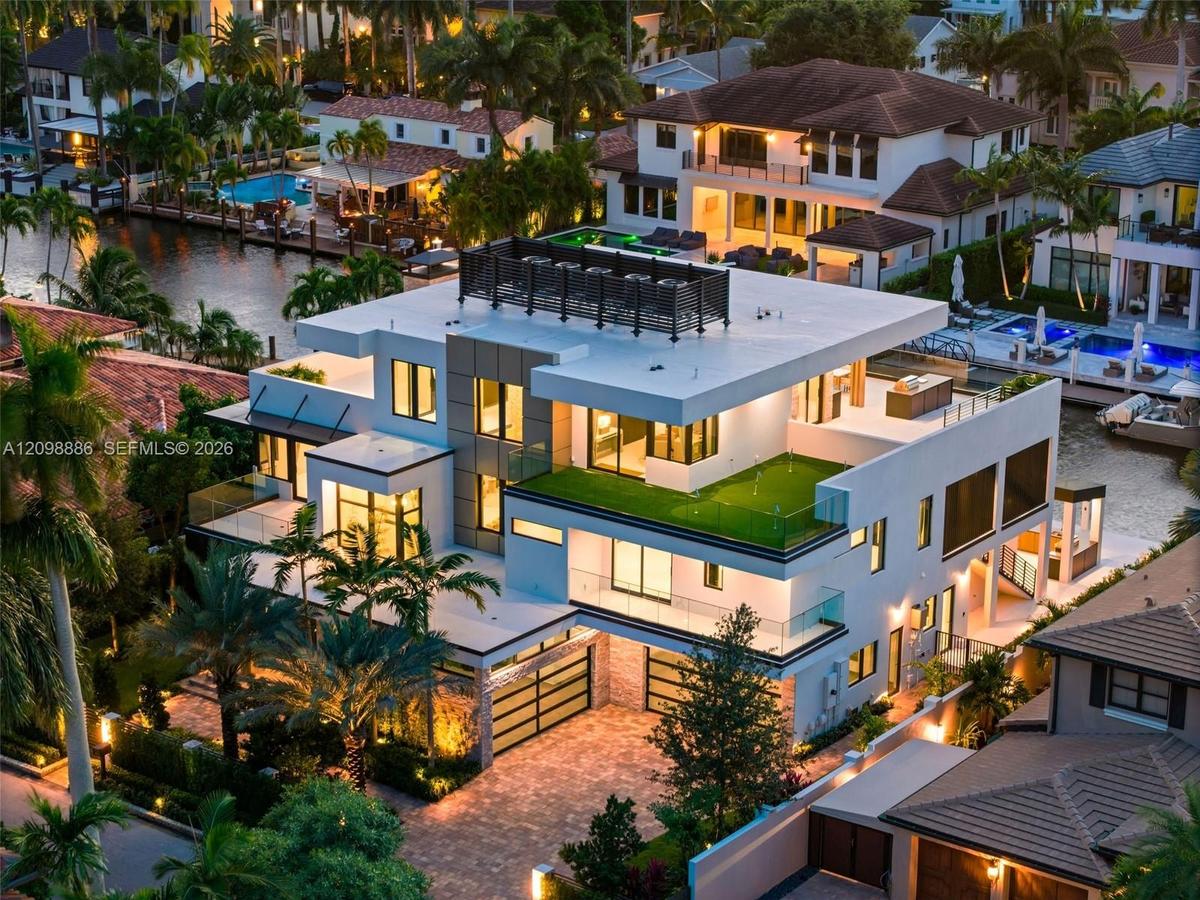 Modern multi-level estate featuring expansive flat-roof terraces, artificial turf accents, floor-to-ceiling glass paneling, a paved driveway, and priv