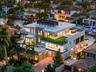 Modern multi-level estate featuring expansive flat-roof terraces, artificial turf accents, floor-to-ceiling glass paneling, a paved driveway, and priv