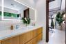 Floating dual-sink vanity with ribbed wood-finish cabinetry, solid-surface countertop, integrated LED-backlit mirror, and polished chrome faucets