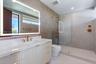 Floating vanity with ribbed cabinetry, solid surface countertop, integrated LED-backlit mirror, and brass-tone fixtures